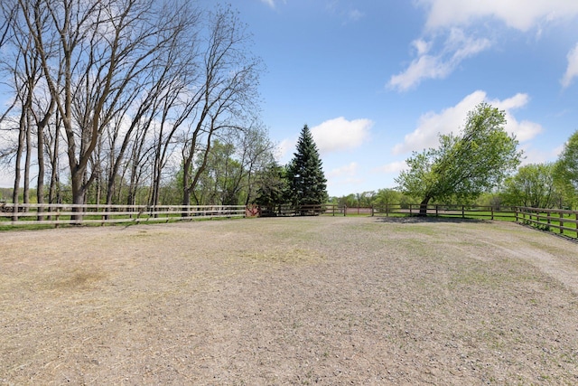 view of yard with a view of rural / pastoral area, an enclosed riding area, and fence