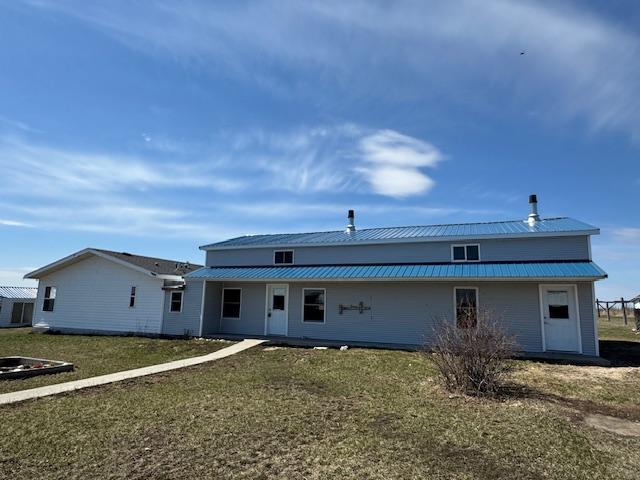 rear view of house featuring a yard and metal roof