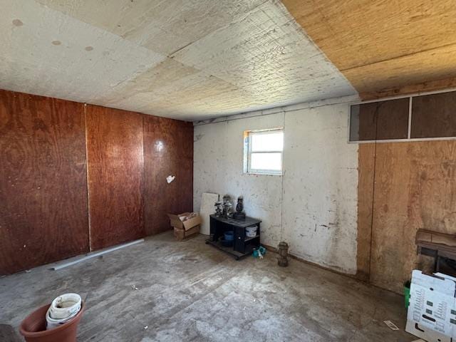 below grade area featuring wooden walls and a wood stove