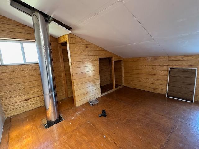 additional living space featuring wooden walls and lofted ceiling