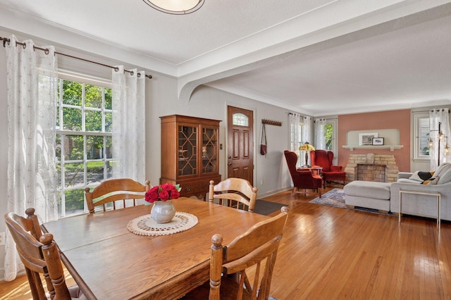 dining space featuring light wood-type flooring, crown molding, a textured ceiling, and baseboards