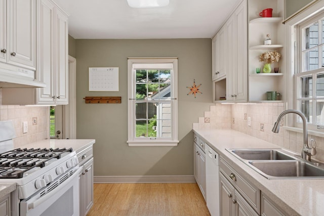 kitchen featuring white appliances, a sink, under cabinet range hood, and open shelves