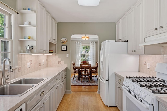 kitchen with gas range gas stove, open shelves, a sink, under cabinet range hood, and light wood finished floors
