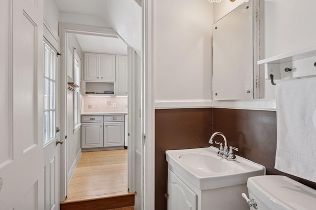 bathroom with decorative backsplash, toilet, wood finished floors, and vanity