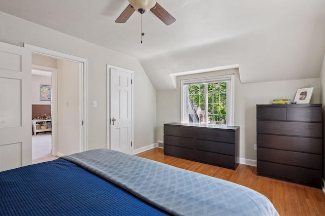 bedroom with wood finished floors, vaulted ceiling, baseboards, and a ceiling fan