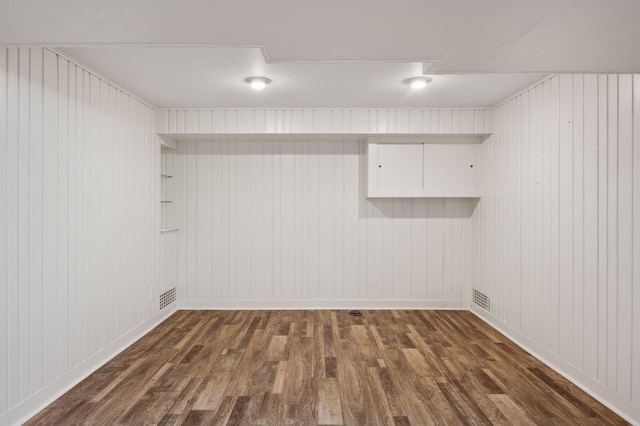 finished basement with wood finished floors, baseboards, and wood walls