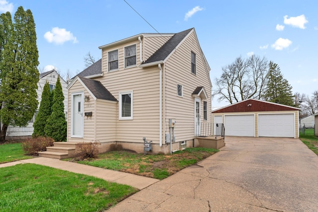 view of front facade featuring a detached garage, a front lawn, a shingled roof, and an outbuilding