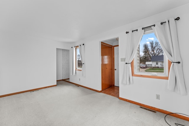 carpeted empty room featuring visible vents, plenty of natural light, and baseboards
