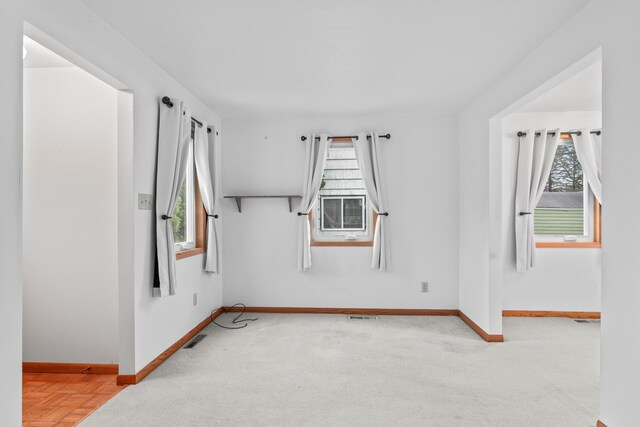 carpeted spare room with visible vents, baseboards, and a healthy amount of sunlight