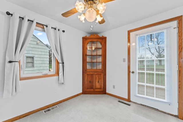 unfurnished room featuring visible vents, ceiling fan, light carpet, and baseboards