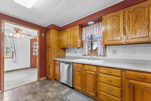 kitchen featuring brown cabinetry, dishwasher, light countertops, and a sink