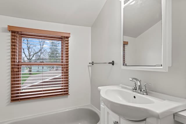 full bathroom featuring a bathing tub, vanity, and vaulted ceiling
