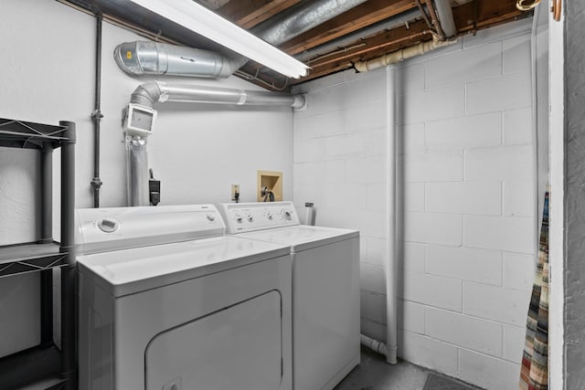 laundry area featuring concrete block wall, washer and clothes dryer, and laundry area