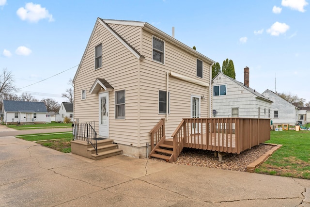 rear view of property featuring a lawn and a deck