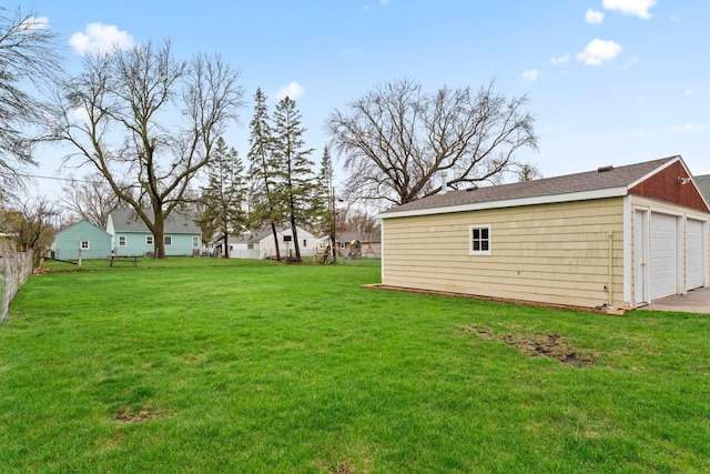view of yard with fence, a garage, and an outbuilding
