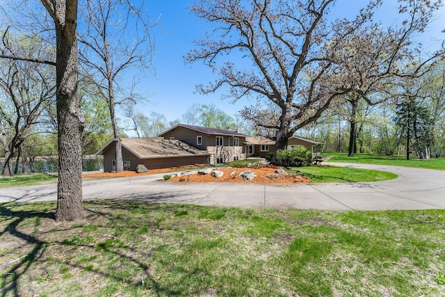 view of front of house featuring curved driveway and a front lawn