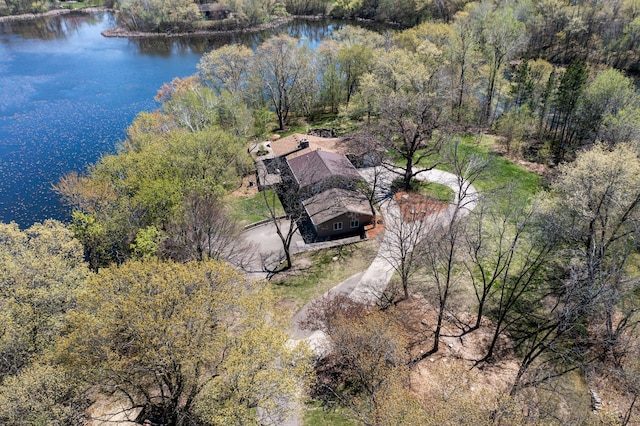 aerial view of property and surrounding area featuring a nearby body of water and a forest