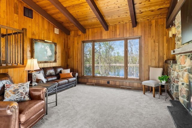 carpeted living room featuring wooden walls, wooden ceiling, a fireplace, and a water view