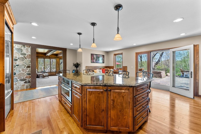 kitchen featuring light wood-style floors, oven, dark stone countertops, recessed lighting, and hanging light fixtures