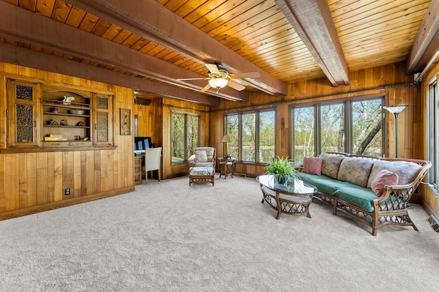 carpeted living room with wooden walls, beam ceiling, healthy amount of natural light, wooden ceiling, and a ceiling fan