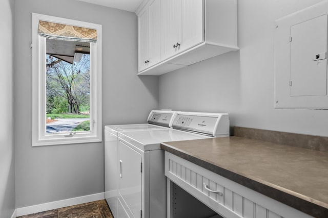 washroom featuring cabinet space, baseboards, washer and clothes dryer, electric panel, and dark stone finish flooring