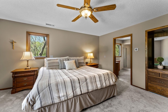 bedroom featuring multiple windows, carpet floors, a textured ceiling, ensuite bathroom, and baseboards