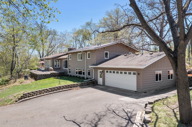 view of front of property with asphalt driveway, an attached garage, a front lawn, a chimney, and roof with shingles