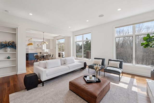 living area featuring baseboards, a notable chandelier, recessed lighting, and wood finished floors