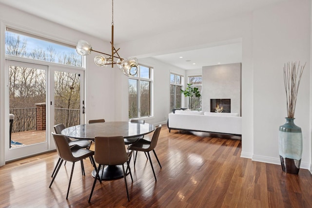 dining space with a lit fireplace, a notable chandelier, visible vents, and wood finished floors