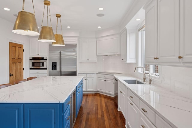 kitchen with a sink, tasteful backsplash, blue cabinets, white cabinetry, and appliances with stainless steel finishes