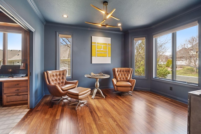 living area with baseboards, ornamental molding, a textured ceiling, and hardwood / wood-style flooring