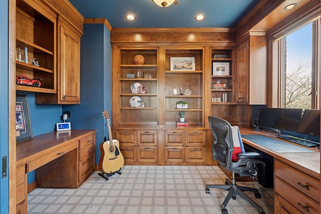 home office with built in desk, crown molding, light colored carpet, and built in shelves