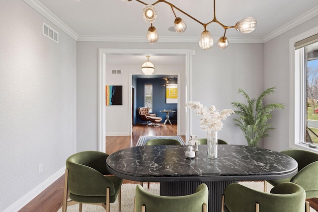 dining room with a wealth of natural light, crown molding, visible vents, and wood finished floors
