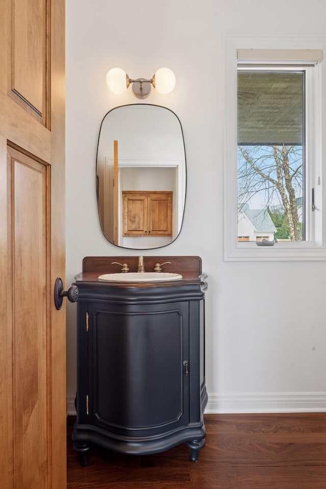 details with vanity, baseboards, and wood finished floors