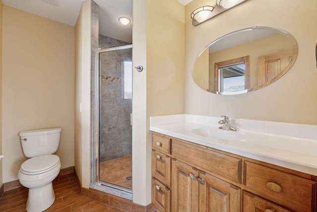 bathroom with a shower stall, vanity, toilet, and wood finish floors