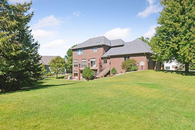 rear view of house featuring a lawn, stairway, and brick siding