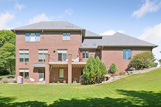back of property with a shingled roof, brick siding, and a lawn
