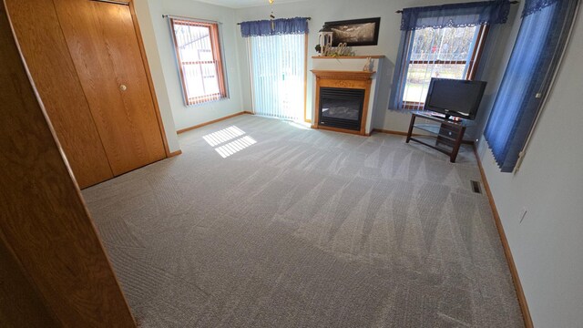 1509 2nd Ave SW, Austin, MN 55912 - unfurnished living room featuring a glass covered fireplace, carpet floors, visible vents, and baseboards