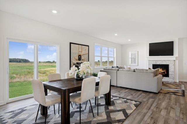 dining space featuring a fireplace, wood finished floors, and recessed lighting