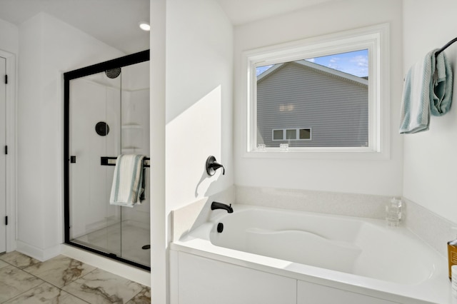bathroom featuring marble finish floor, a garden tub, and a stall shower
