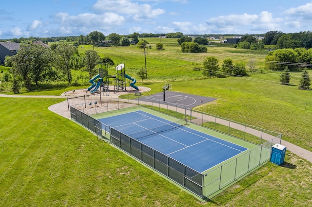 view of tennis court with a yard, fence, and playground community