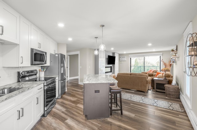 kitchen featuring stainless steel appliances, dark wood-style flooring, recessed lighting, a kitchen island, and white cabinetry