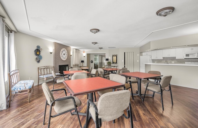 dining area featuring wood finished floors, a fireplace, and baseboards