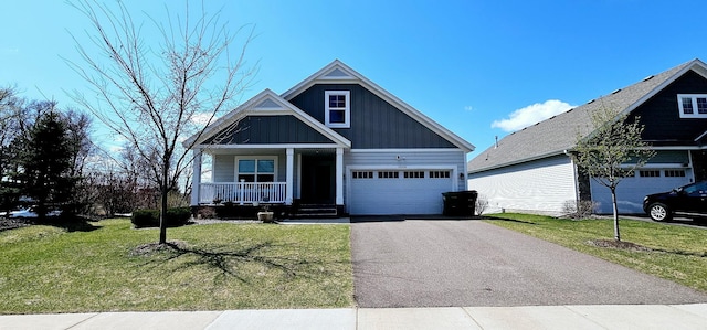 craftsman inspired home with covered porch, board and batten siding, a front lawn, and aphalt driveway