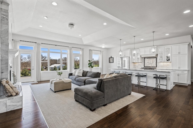 living area with recessed lighting, dark wood finished floors, and a tray ceiling