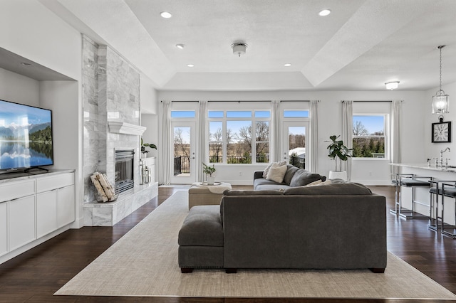 living area with baseboards, recessed lighting, a raised ceiling, dark wood finished floors, and a premium fireplace
