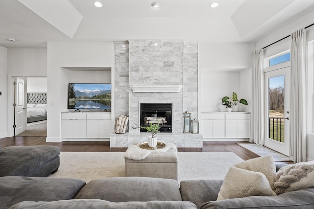 living area featuring a tray ceiling, recessed lighting, wood finished floors, and a premium fireplace