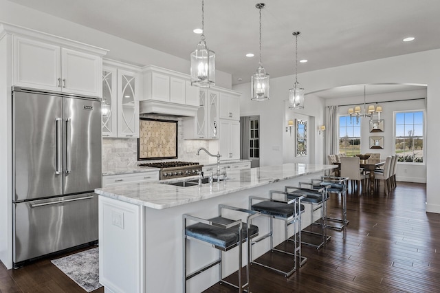 kitchen featuring decorative backsplash, a sink, light stone counters, white cabinets, and stainless steel appliances