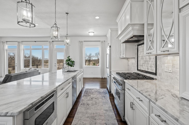 kitchen featuring high end appliances, a spacious island, custom range hood, dark wood finished floors, and backsplash