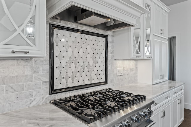 kitchen with light stone countertops, glass insert cabinets, premium range hood, white cabinets, and tasteful backsplash